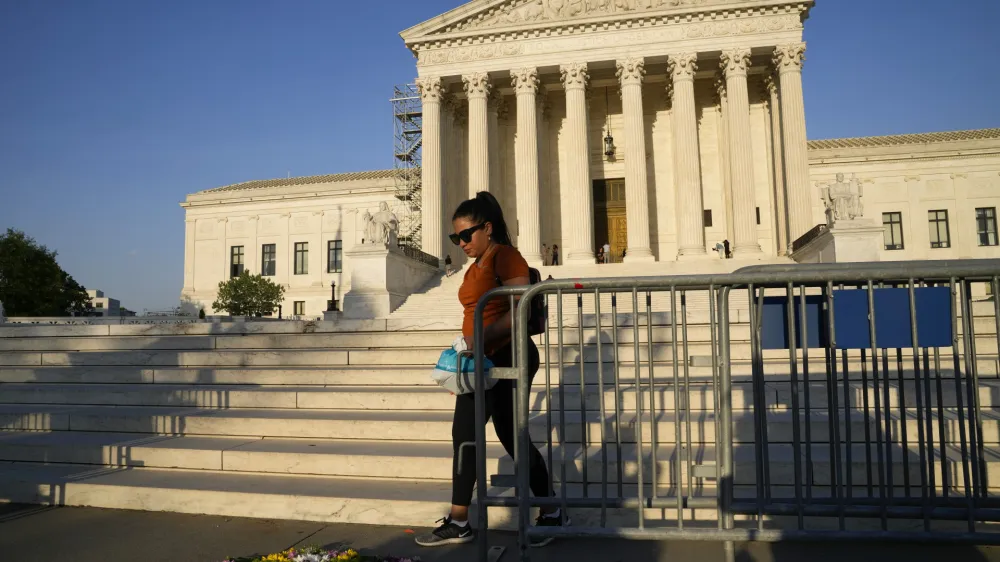 A person walks by flowers that are in the shape of a uterus outside the Supreme Court on Friday, April 21, 2023, in Washington. The Supreme Court has preserved women's access to a drug used in the most common method of abortion, rejecting lower-court restrictions while a lawsuit continues. The justices on Friday granted emergency requests from the Biden administration and New York-based Danco Laboratories, maker of the drug mifepristone. (AP Photo/Jacquelyn Martin)