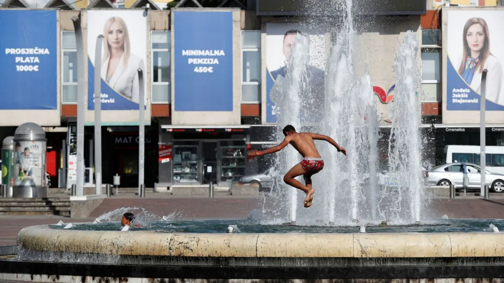 A kid jumps into a fountain in front of campaign posters on main city square as Montenegro prepares for snap parliamentary elections, in Podgorica, Montenegro June 8, 2023. REUTERS/Stevo Vasiljevic