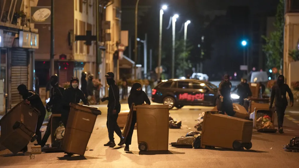 Protesters block a street with garbage cans in Colombes, outside Paris, France, Saturday, July 1, 2023. French President Emmanuel Macron urged parents Friday to keep teenagers at home and proposed restrictions on social media to quell rioting spreading across France over the fatal police shooting of a 17-year-old driver. (AP Photo/Lewis Joly)