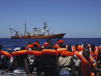﻿FILE - In this Thursday June 23, 2016 file photo, Migrants aboard a dinghy in the Mediterranean Sea wait to be rescued by members of the aid group Medecins Sans Frontieres (MSF) and the rescue group SOS Mediterranee Rescuers of SOS Mediterranee. Doctors Without Borders said Saturday, Aug. 12, 2017, it is temporarily suspending the activity of its rescue ship due to alleged threats from Libyaâ€™s coast guard, which has increasingly become more aggressive in patrolling the waters off its coasts where human traffickers launch boats crowded with migrants desperate to reach Europe. (AP Photo/Bram Janssen, File)