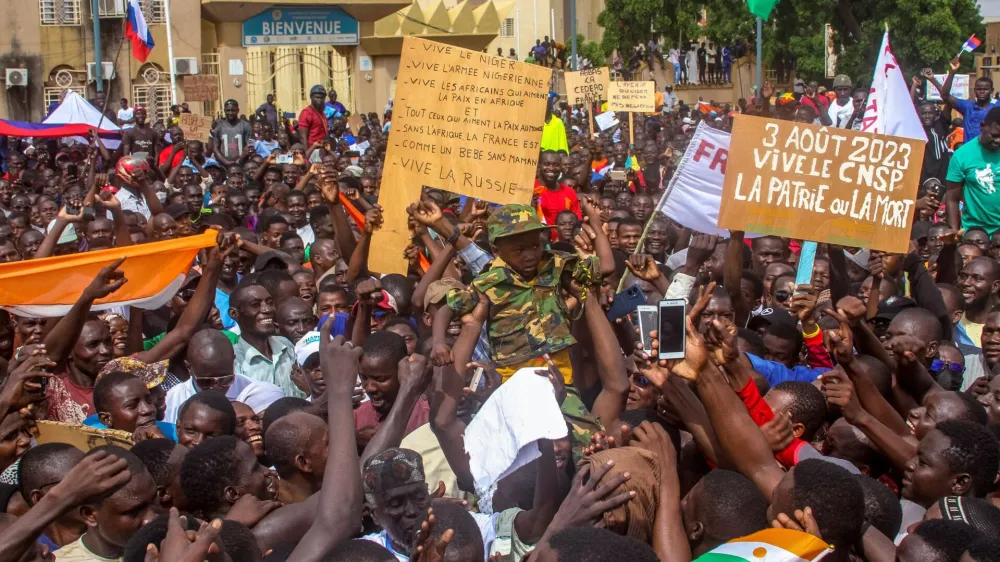 Men a hold a child dressed in military uniform as they gather with thousands of anti-sanctions protestors in support of the putschist soldiers in the capital Niamey, Niger August 3, 2023. REUTERS/Mahamadou Hamidou NO RESALES. NO ARCHIVES