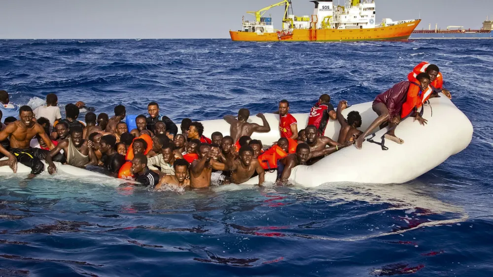In this photo taken on Sunday, April 17, 2016 migrants ask for help from a dinghy boat as they are approached by the SOS Mediterranee's ship Aquarius, background, off the coast of the Italian island of Lampedusa. The European Union's border agency says the number of migrants crossing the Mediterranean Sea to Italy more than doubled last month. Frontex said in a statement on Monday that almost 9,600 migrants attempted the crossing, one of the most perilous sea voyages for people seeking sanctuary or jobs in Europe. (Patrick Bar/SOS Mediterranee via AP)