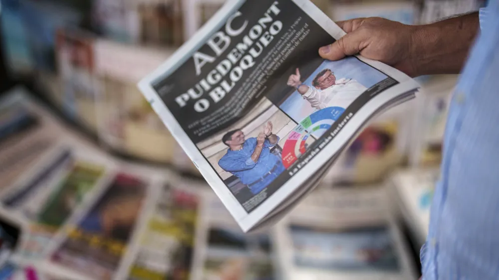 FILE - A man picks up a newspaper with pictures of Spain's Prime Minister and Socialist Workers' Party Pedro Sanchez, left, and Alberto Feijoo, leader of the mainstream conservative Popular Party of the Spain's general election celebrated yesterday in Madrid, Spain, on July 24, 2023. King Felipe VI began consultations with leaders of Spain's political parties Monday Aug. 21, 2023 to see which one has the best chance to form a government following an inconclusive national election last month. (AP Photo/Manu Fernandez, File)