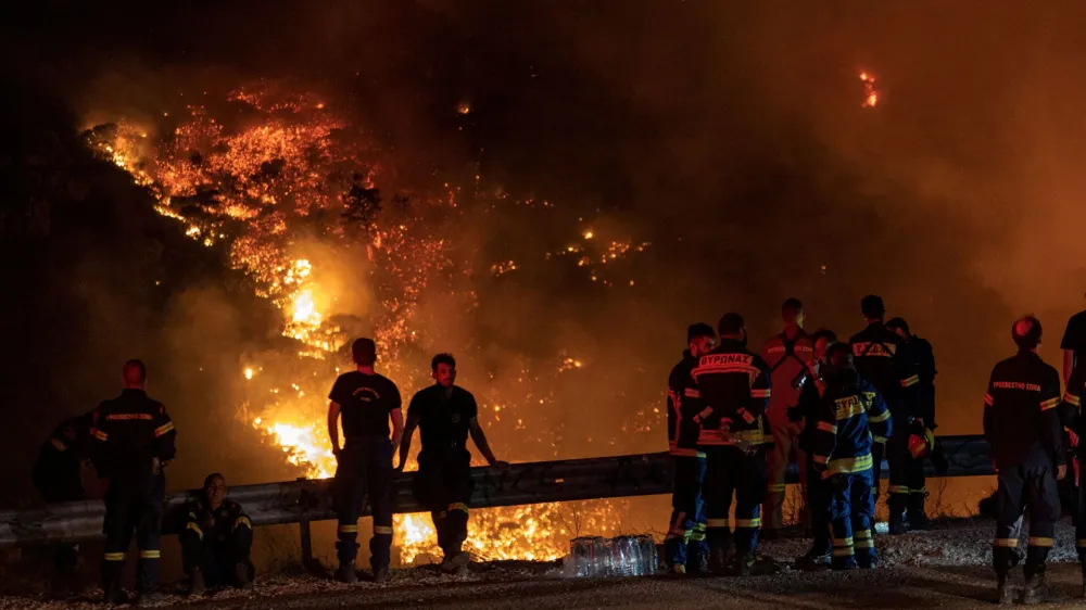 Firefighters look at a wildfire burning on Mount Parnitha, in Athens, Greece, August 24, 2023. REUTERS/Nicolas Economou   TPX IMAGES OF THE DAY