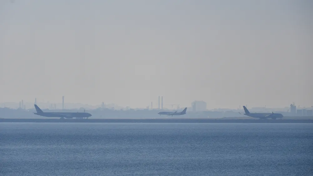 Airplanes are seen on the runway as smoke blankets the skyline in Sydney, Wednesday, September 13, 2023. Parts of Sydney are blanketed in a smoke haze caused by weekend hazard reduction burns as fire authorities prepare the state for the looming bushfire season. (AAP Image/Bianca De Marchi) NO ARCHIVING