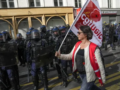 A demonstrator walks past police officers with a union flag during a protest against police violence, Saturday, Sept. 23, 2023. Families, community groups and far-left activists marched in cities around France on Saturday to decry racism and police brutality, putting authorities on edge at a time when French police are deployed en masse for a string of high-security events. (AP Photo/Michel Euler)