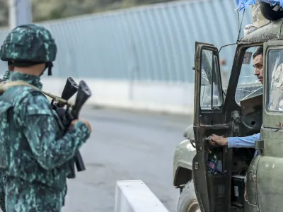 Sergey Astsetryan, an ethnic Armenian resident of Nagorno-Karabakh, right, says goodbye to Azerbaijani border guard servicemen after they checked his Soviet-made vehicle at the Lachin checkpoint on the way from Nagorno-Karabakh to Armenia, in Azerbaijan, Sunday, Oct. 1, 2023. Astsetrayn was one of the last residents of Nagorno-Karabakh to drive out of the region in his own vehicle as part of a grueling weeklong exodus of over 100,000 people — more than 80% of the residents — after Azerbaijan reclaimed the area in a lightning military operation. (AP Photo/Aziz Karimov)