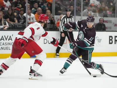 Anaheim Ducks' Trevor Zegras (11) shoots under defense by Carolina Hurricanes' Brent Burns (8) during the third period of an NHL hockey game Sunday, Oct. 15, 2023, in Anaheim, Calif. The Ducks won 6-3. (AP Photo/Jae C. Hong)