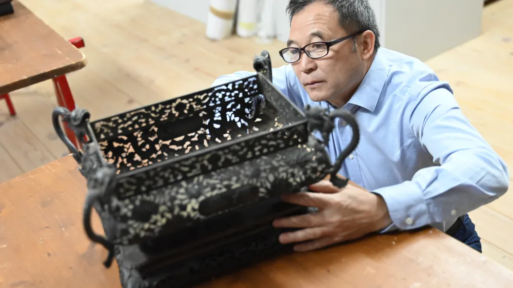 Kustos Guo Fuxiang si ogleduje enega od predmetov, ki jih je Skušek pred sto leti v Slovenijo pripeljal iz Kitajske.
