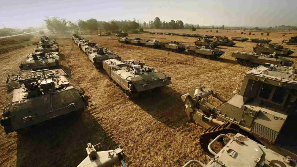 Israeli tanks and armoured personnel carriers (APC) are parked on a field in the Mefalsim area on the Israeli-Gaza border June 26, 2006. Israel on Sunday threatened a strong military response after Palestinian militants emerged from a long tunnel dug into Israel, killed two soldiers, wounded four and kidnapped another at an outpost near the Egyptian border. REUTERS/Yannis Behrakis (ISRAEL)