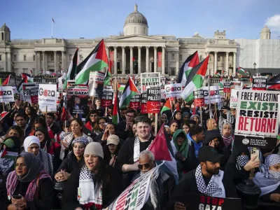 Protesters hold placards and Palestinian flags during a pro-Palestinian rally in Trafalgar Square, London, Saturday Nov. 4, 2023. (Victoria Jones/PA via AP)