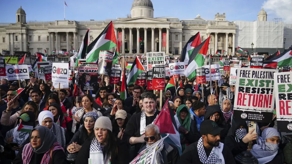 Protesters hold placards and Palestinian flags during a pro-Palestinian rally in Trafalgar Square, London, Saturday Nov. 4, 2023. (Victoria Jones/PA via AP)
