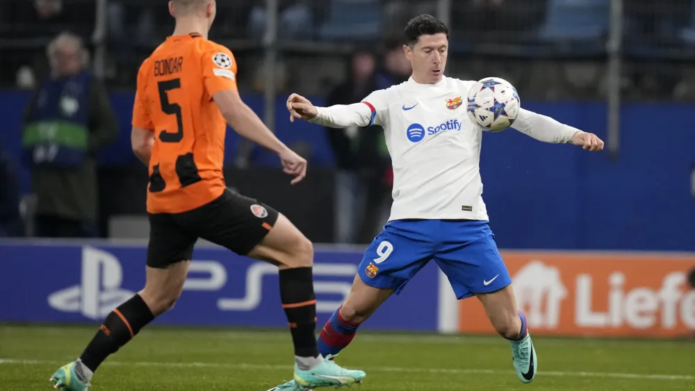 Barcelona's Robert Lewandowski, right, controls the ball as Shakhtar's Valeriy Bondar defends during the Champions League Group H soccer match between Shakhtar Donetsk and Barcelona, at the Volksparkstadion in Hamburg, Germany, Tuesday, Nov. 7, 2023. (AP Photo/Matthias Schrader)