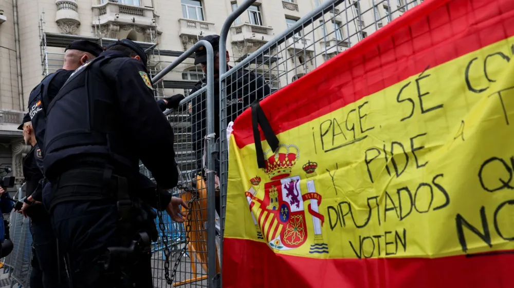 Police members work next to a Spanish flag hanged on fencing during a protest outside the Spanish parliament, as the investiture debate kicks off after Spain's socialists reached a deal with the Catalan separatist Junts party for government support, a pact which involves amnesties for people involved with Catalonia's failed 2017 independence bid, in Madrid, Spain November 15, 2023. REUTERS/Violeta Santos Moura