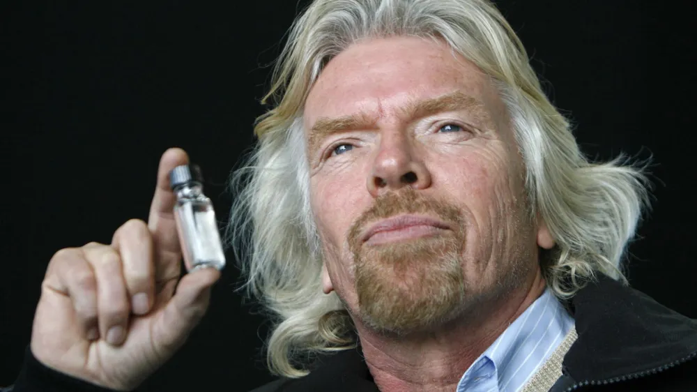 Virgin Group chairman Richard Branson holds up a bottle filled with what he says is biofuel, before the world's first commercial biofuel flight of a Virgin Atlantic Boeing 747 aircraft to Amsterdam from Heathrow Airport in London February 24, 2008. Nuts picked from Amazon rainforests helped fuel the world's first commercial airliner flight powered by renewable energy on Sunday.   REUTERS/Luke MacGregor  (BRITAIN)