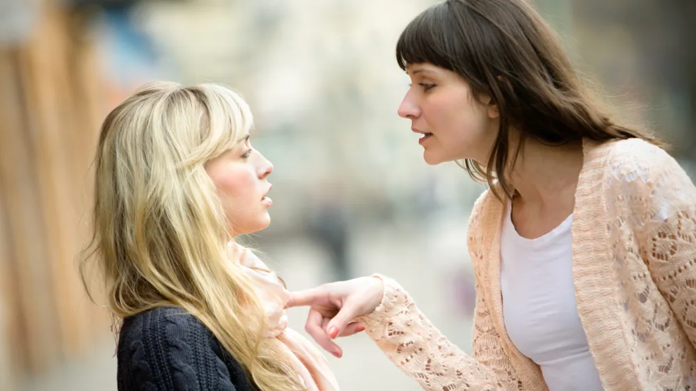 Two women talking to each other and arguing.