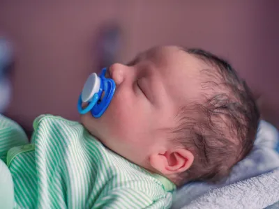 Face profile portrait of a sleeping newborn baby with a pacifier in his mouth