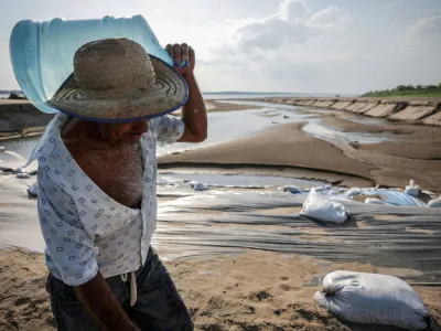 FILE PHOTO: A man carries a water jug during a historic drought in the Amazon at the dry riverbed of the Paraua river in Careiro da Varzea, Amazonas state, Brazil October 26, 2023.    REUTERS/Bruno Kelly/File Photo