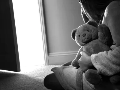 BTA0N2 Young girl sitting holding a teddy bear, back view.<br>spolna zloraba otroci otrok