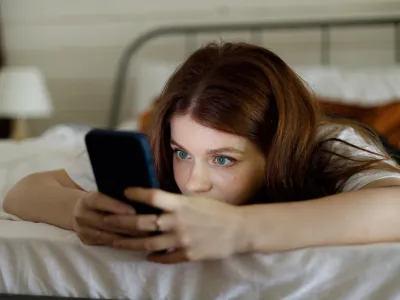 Night chat on smartphone. A young girl surfs the internet in bed, plays games or watches videos. Phone addiction.
