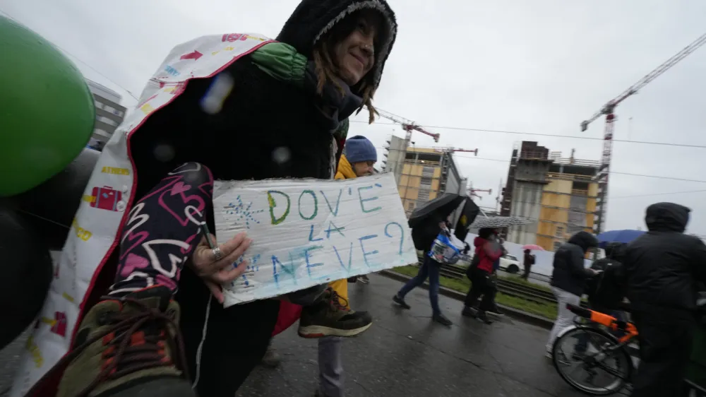 Activists of the C.I.O Comitato Insostenibili Olimpiadi (Unsustainable Olympics Commetee) hold a sign in Italian reading: "Where is the snow?"" as they march in front of the building site of the 2026 Winter Olympic village in Milan, northern Italy, Saturday, Feb. 10, 2024, to protest the prospected costs of the 2026 Winter Olympics that will be disputed in Milan and Cortina d'Ampezzo in the Dolomites. (AP Photo/Luca Bruno)