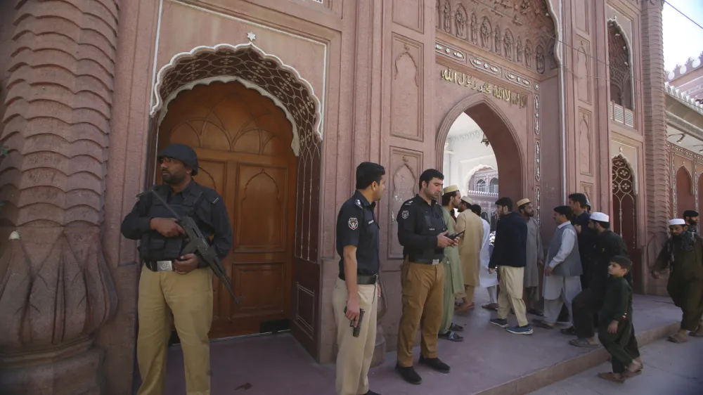 Police officers stand guard as people arrive to attend first Friday prayer during the Muslim's holy fasting month of Ramadan, at the historical Sunehri mosque, in Peshawar, Pakistan, Friday, March 15, 2024. (AP Photo/Muhammad Sajjad)