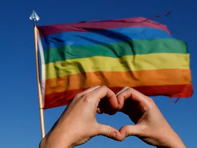 A person holds their hands in the shape of a heart in front of a pride flag during a march for solidarity for the those affected after a mass shooting at LGBTQ nightclub Club Q, in Colorado Springs, Colorado, U.S. November 26, 2022. REUTERS/Isaiah J. Downing   TPX IMAGES OF THE DAY
