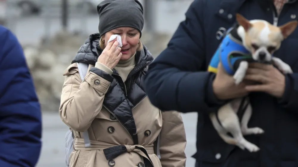 A woman reacts as she comes to place flowers at the fence next to the Crocus City Hall, on the western edge of Moscow, Russia, Saturday, March 23, 2024, following an attack Friday, for which the Islamic State group claimed responsibility. Russian officials say more than 90 people have been killed by assailants who burst into a concert hall and sprayed the crowd with gunfire. (AP Photo/Vitaly Smolnikov)