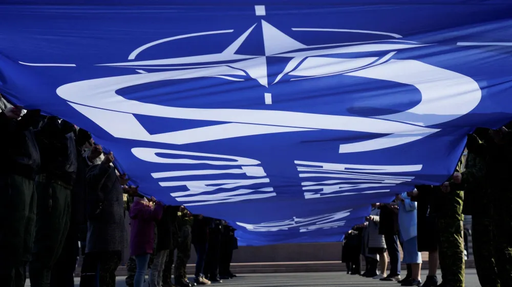 People hold a giant flag with NATO sign as Latvia celebrates anniversary to joining alliance in Riga, Latvia March 28, 2024. REUTERS/Ints Kalnins