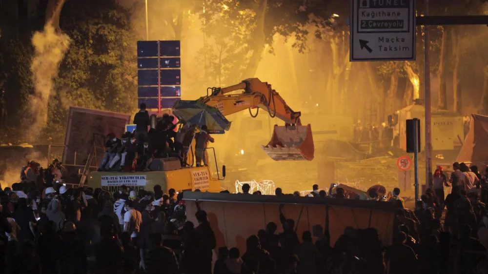 Anti-government protesters behind barricades and on an excavator clash with riot police as they try to march to the office of Turkey's Prime Minister Tayyip Erdogan in Istanbul early June 3, 2013. Turkish protesters clashed with riot police into the early hours of Monday with some setting fire to offices of the ruling AK Party as the fiercest anti-government demonstrations in years entered their fourth day. Turkey's streets were calm in the morning after a night of noisy protests and violence in major cities. REUTERS/Stringer (TURKEY - Tags: POLITICS CIVIL UNREST TPX IMAGES OF THE DAY)
