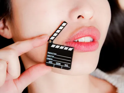 ﻿Face detail of sensual woman lips, no eyes, with hand holding little movie clapper board