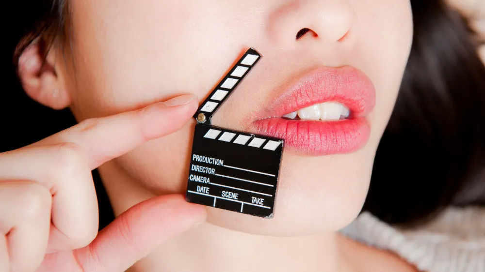 ﻿Face detail of sensual woman lips, no eyes, with hand holding little movie clapper board