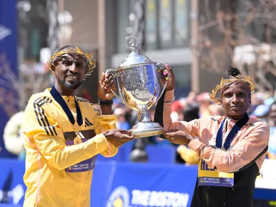 Apr 15, 2024; Boston, MA, USA; Sisay Lemma of Ethiopia and Hellen Obiri of Kenya pose at the finish line with the winners trophy at the 2024 Boston Marathon. Mandatory Credit: Eric Canha-USA TODAY Sports