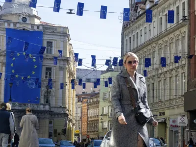 A woman walks under European Union flags placed in one of the main streets in Sarajevo, Bosnia, Thursday, March 21, 2024. European Union leaders meeting in Brussels are expected to give a greenlight to Bosnia and Herzegovina to open membership talks once certain conditions are met. (AP Photo/Eldar Emric)