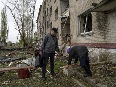 A volunteer helps Olga, 79, walk down some steps from her apartment which was heavily damaged by a Russian airstrike, during her evacuation, in Lukiantsi, Kharkiv region, Ukraine, on Tuesday, April 16, 2024. (AP Photo/Evgeniy Maloletka)