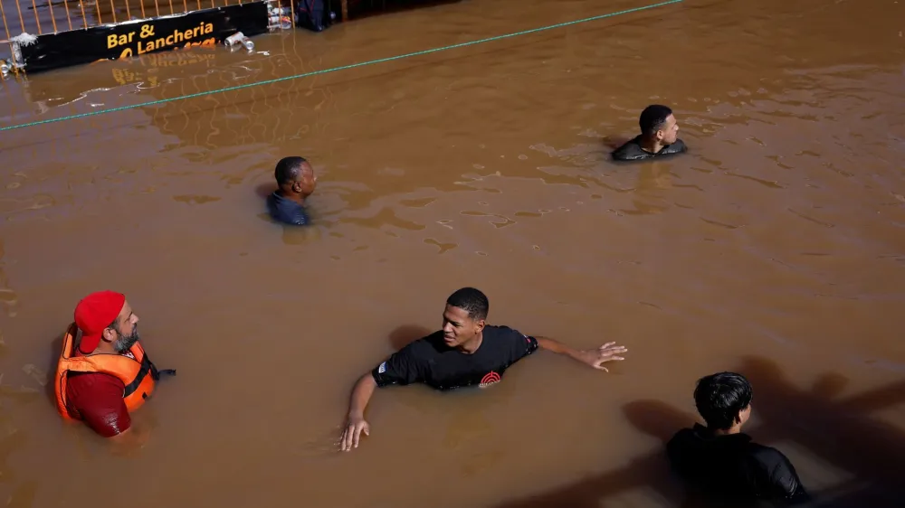 People wade through flood waters in Canoas, at the Rio Grande do Sul state, Brazil, May 5, 2024. REUTERS/Amanda Perobelli