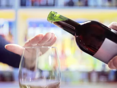 Womans hand rejecting more alcohol from wine bottle in bar