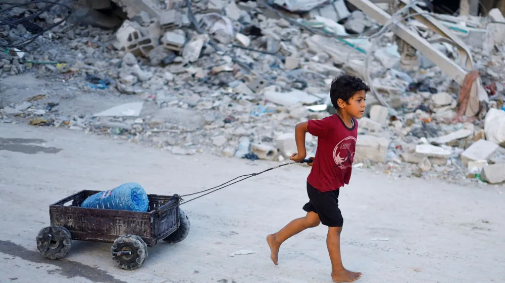 FILE PHOTO: A Palestinian child pulls a water container, amid the ongoing conflict between Israel and Hamas, in southern Gaza City, in the Gaza Strip, June 3, 2024. REUTERS/Mohammed Salem/File Photo