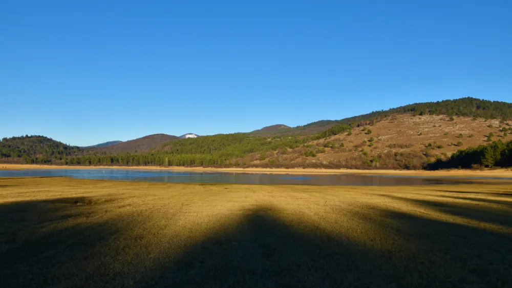 View of Petelinjsko jezero intermittent karst lake in Notranjska, Slovenia with forest covered hills