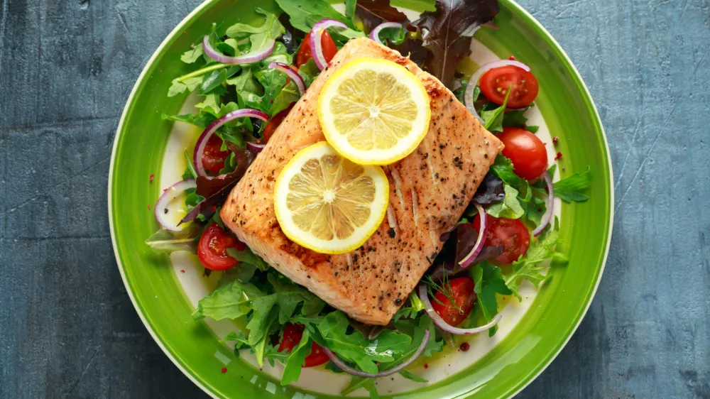 Baked salmon steak with tomato, onion, mix of green leaves salad in a plate. healthy food. / Foto: Drong