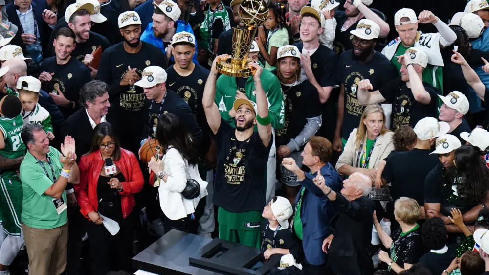 Jun 17, 2024; Boston, Massachusetts, USA; Boston Celtics forward Jayson Tatum (0) celebrates with the trophy on the podium after defeating the Dallas Mavericks in the 2024 NBA Finals at TD Garden. Mandatory Credit: David Butler II-USA TODAY Sports