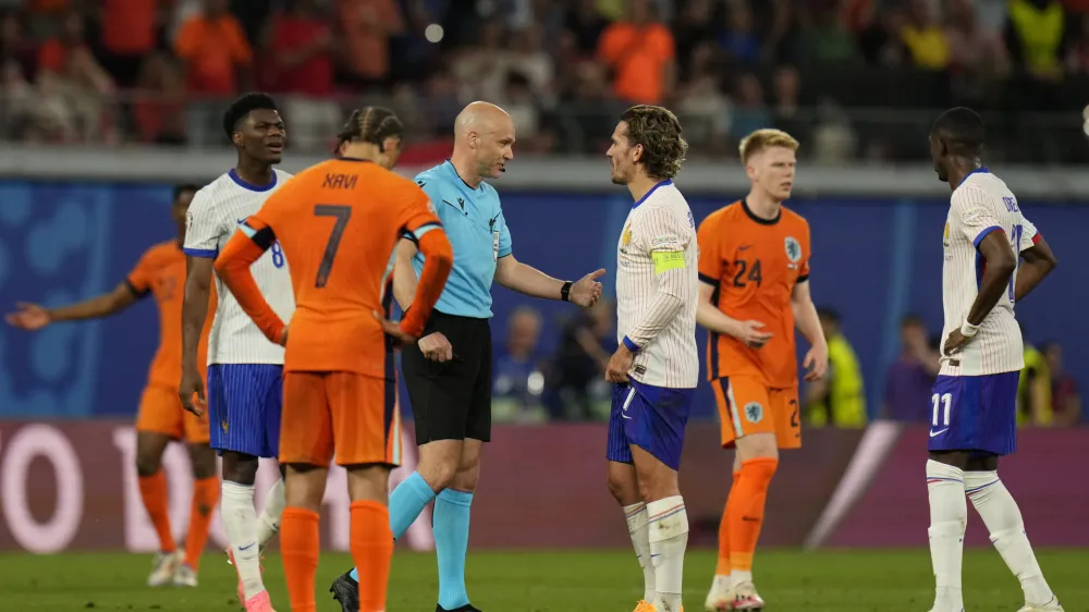Referee Anthony Taylor is surrounded by players as he waits for a fourth official decision on a goal by Xavi Simons of the Netherlands that was then disallowed for offside during the Group D match between the Netherlands and France at the Euro 2024 soccer tournament in Leipzig, Germany, Friday, June 21, 2024. (AP Photo/Hassan Ammar)