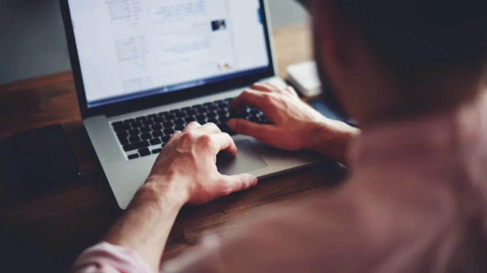 Cropped image of a young man working on his laptop in a coffee shop, rear view of business man hands busy using laptop at office desk, young male student typing on computer sitting at wooden table
