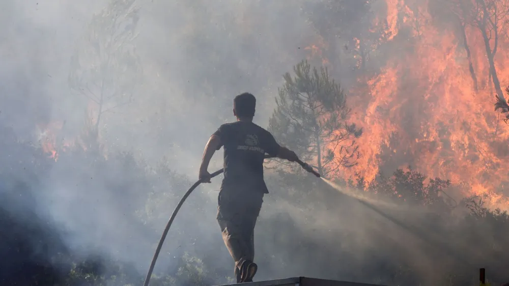A volunteer tries to extinguish a wildfire burning in Stamata, near Athens, Greece, June 30, 2024. REUTERS/Giorgos Moutafis