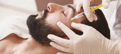 Bearded man getting anti-wrinkle face filler treatment by beautician / Foto: Oleksandra Polishchuk