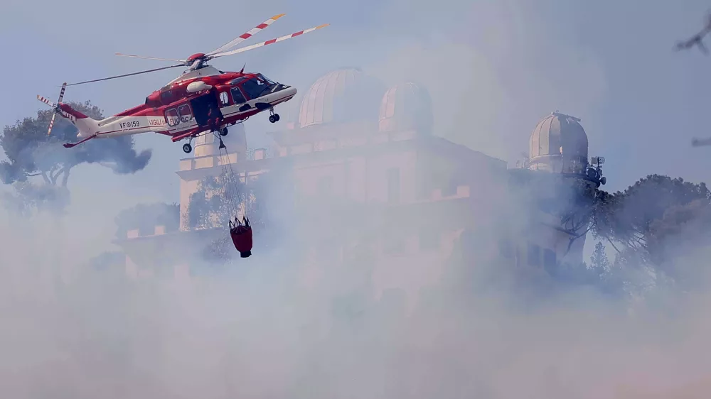 31 July 2024, Italy, Rome: A fire-fighting helicopter tries to extinguish the fire near the courthouse in the Monte Mario area. Photo: Cecilia Fabiano/LaPresse via ZUMA Press/dpa