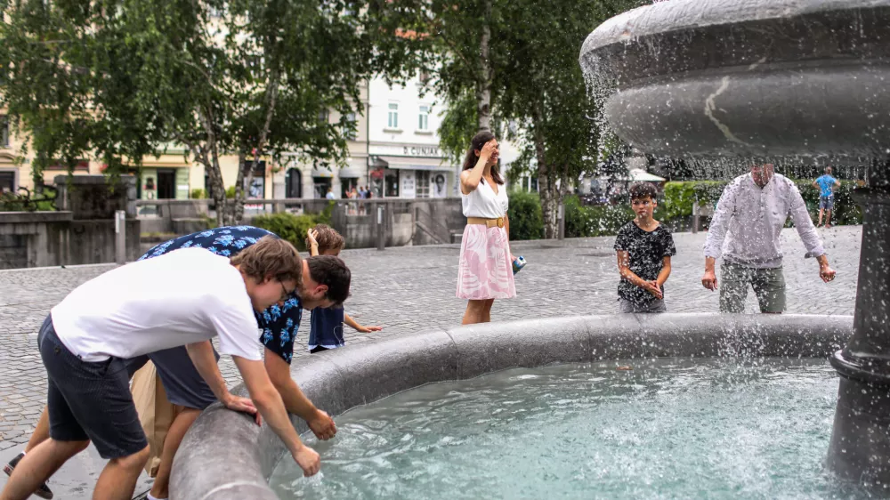 - Mimoidoči v Ljubljani se sku&scaron;ajo ohladiti v vodnjaku na Novem trgu.- 10.07.2024. - Vročinski val je zajelSlovenijo s temperaturima preko 30 stopinj.//FOTO: Bojan Velikonja