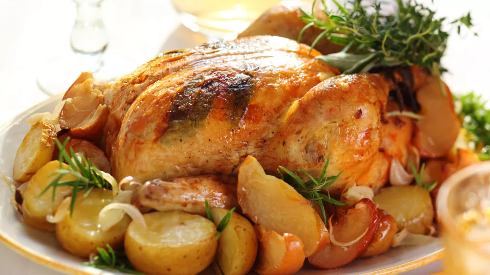 Whole roasted chicken with potatoes and apples on white plate / Foto: Elenagaak