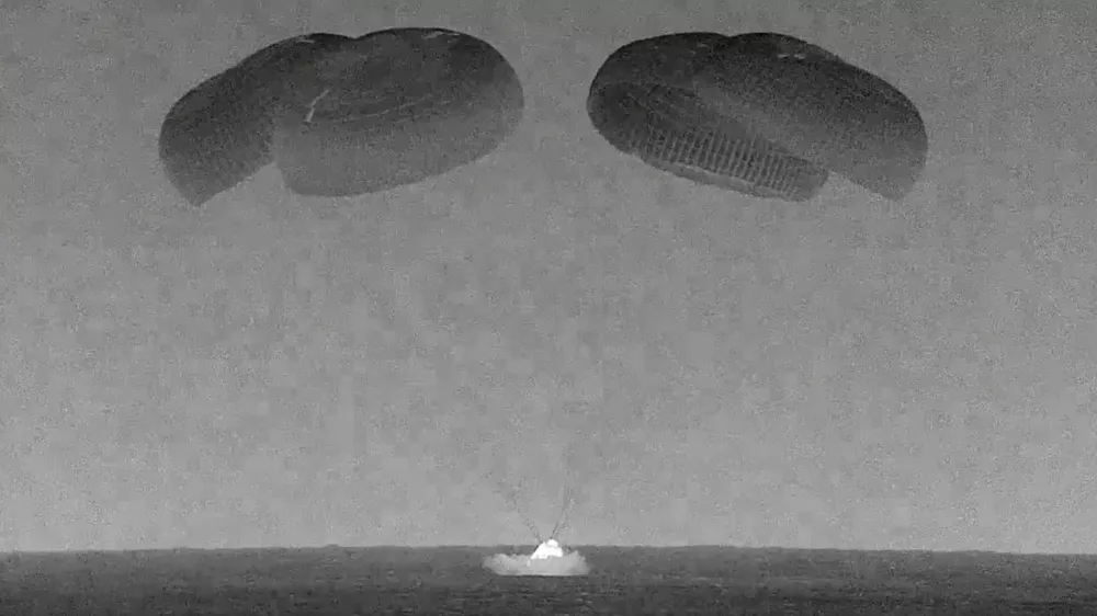 This black and white, thermal image made from SpaceX video shows its capsule, center, carrying tech entrepreneur Jared Isaacman with his crew as it splashes down in the Gulf of Mexico near Florida's Dry Tortugas early Sunday, Sept. 15, 2024. (SpaceX via AP)