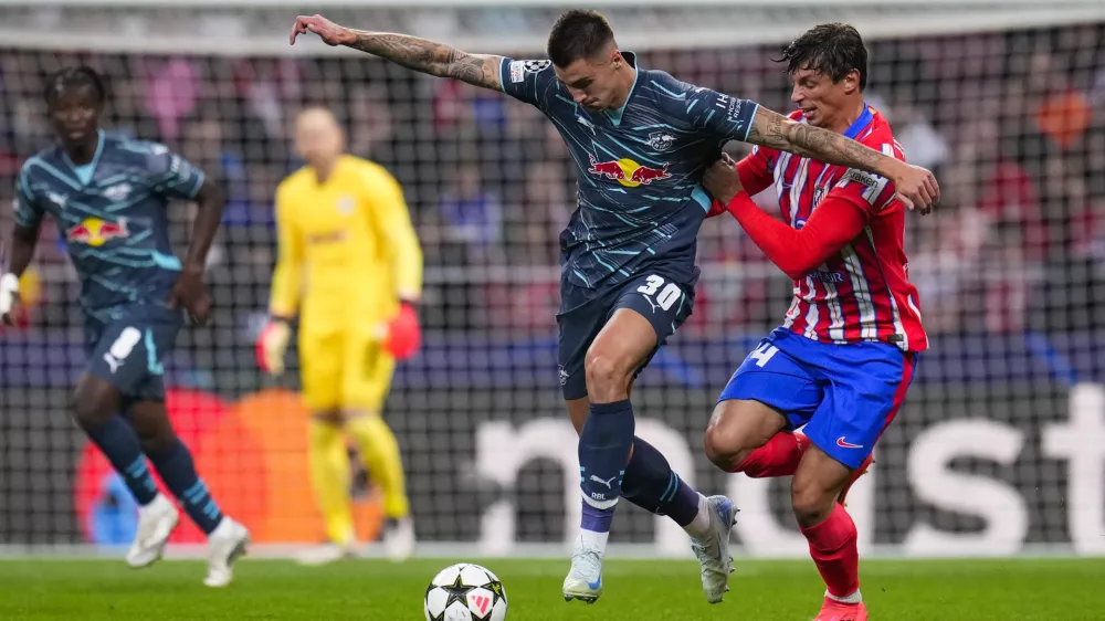 Leipzig's Benjamin Sesko, left, vies for the ball with Atletico Madrid's Robin Le Normand during to the Champions League opening phase soccer match between Atletico Madrid and RB Leipzig at the Metropolitano stadium, in Madrid, Thursday, Sept. 19, 2024. (AP Photo/Manu Fernandez)